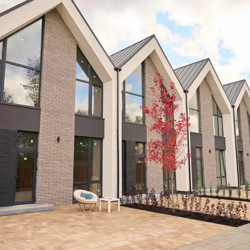 Rij woningen met puntgevels, grote glaspartijen en donkere kozijnen